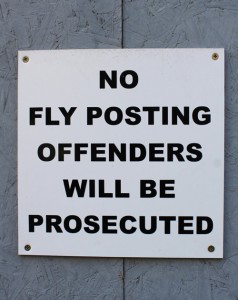 Photograph of sign on boards: No Fly Posting Offenders will be Prosecuted